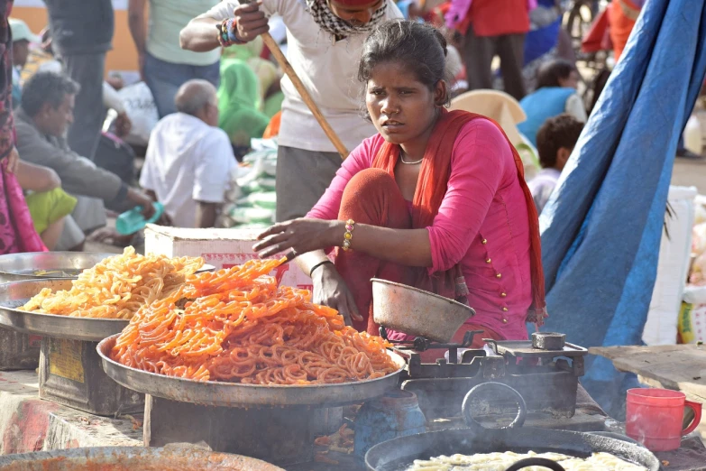 a woman cooking food at an outdoor market, samikshavad, spaghetti monster, snacks, orange, hundreds of them