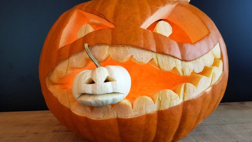 a carved pumpkin sitting on top of a wooden table, a picture, by Tom Carapic, pixabay, large mouth with teeth, white, 🕹️ 😎 🔫 🤖 🚬, up close picture