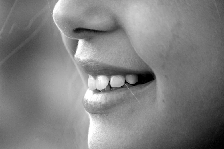 a black and white photo of a woman's smile, pexels, realism, chewing, close - up profile, tooth, pretty aquiline nose