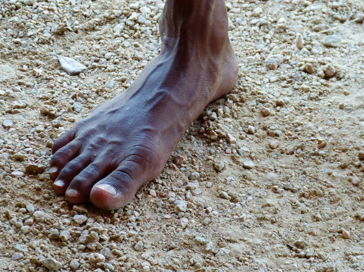 a close up of a person's foot in the sand, by Dietmar Damerau, figuration libre, jamaican, on an indian street, chiseled jaw, adam ondra