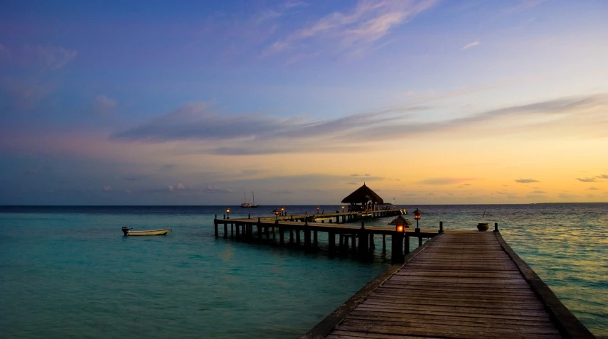 a dock in the middle of a body of water, on the beach at sunset, maldives in background, 6 4 0, uncropped