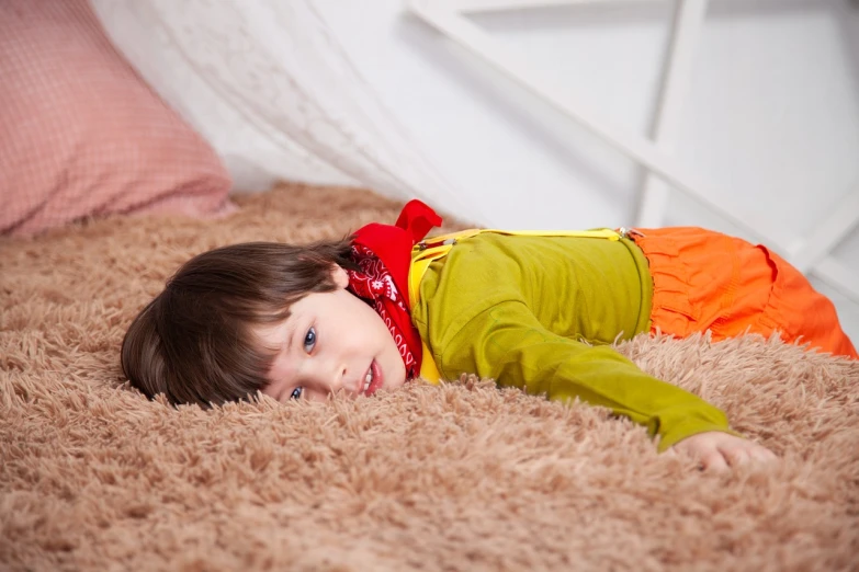 a little girl laying on top of a brown rug, a stock photo, by Ludovit Fulla, shutterstock, boy's room, costume, youthful colours, dynamic!!