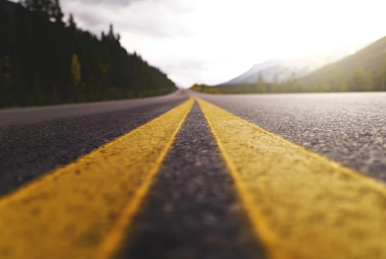 a yellow line in the middle of a road, by Kurt Roesch, unsplash, realism, mountains background, stock footage, smooth.sharp focus, 4 k vertical wallpaper