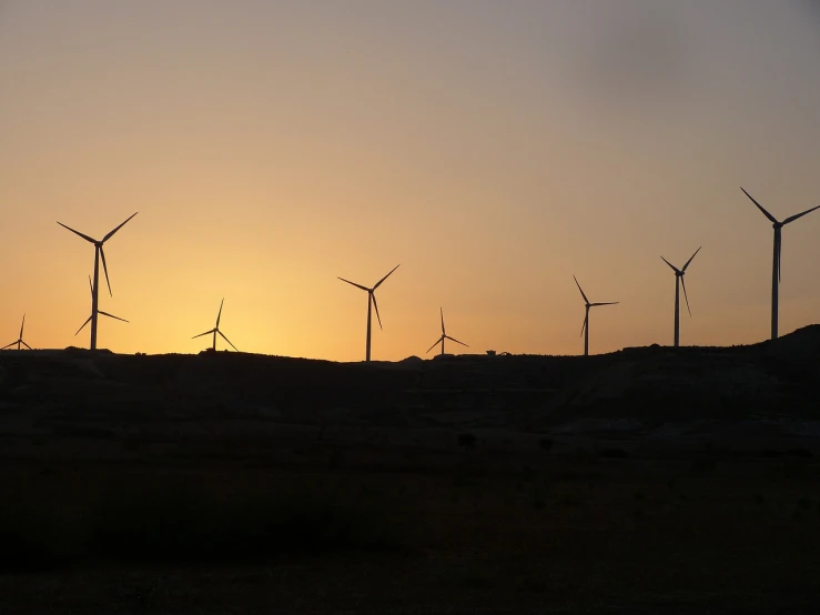 a group of wind turbines sitting on top of a hill, by Alexis Grimou, hurufiyya, sunset in the desert, mines, ((sunset)), turnaround