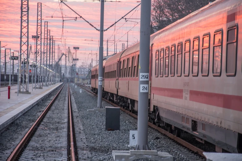 a train traveling down train tracks next to a train station, a picture, sunset photo, reportage photo, maintenance photo, supersonic trains and passengers