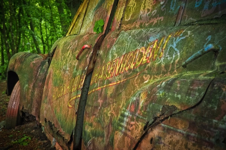 an old truck sitting in the middle of a forest, by Raymond Normand, graffiti, hdr detail, stained antique copper car paint, tattered green dress, etched inscriptions