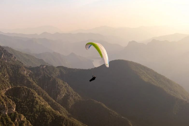 a person that is in the air with a parachute, by Julian Allen, pexels contest winner, brazilian, traveling through the mountains, in a gentle green dawn light, high angle uhd 8 k