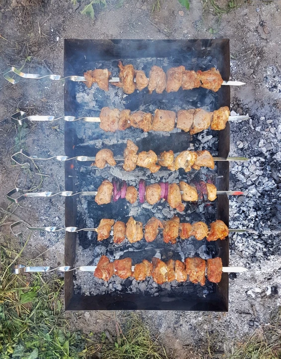 a close up of a grill with skewers on it, a photo, by Aleksander Kotsis, hurufiyya, above view, camp, transformation, rectangular