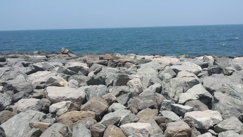 a large pile of rocks next to the ocean, a picture, new jersey, background image, rock walls, near a jetty
