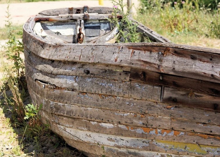 a wooden boat sitting on top of a grass covered field, a picture, by Richard Carline, pixabay, side view close up of a gaunt, dull flaking paint, front side full, reclaimed lumber