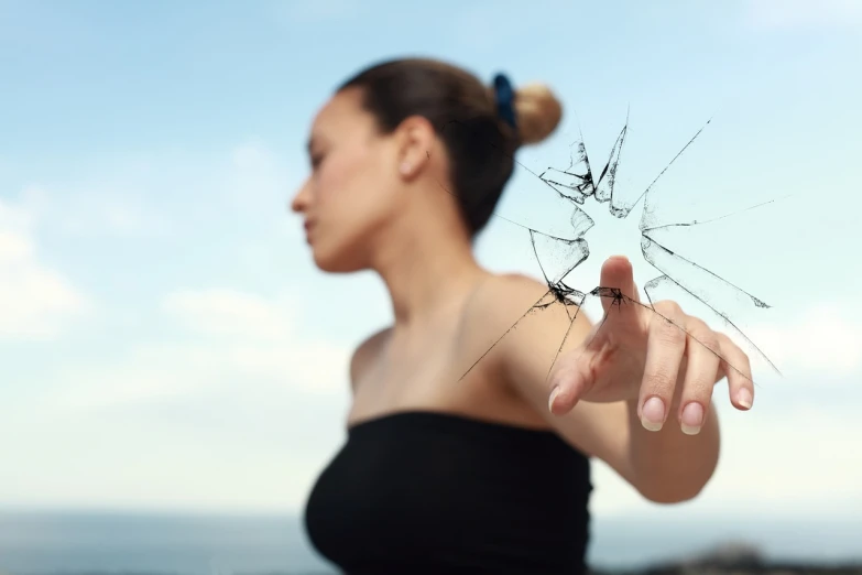 a woman holding a broken glass in front of her face, auto-destructive art, without text, half-woman half-butterfly, cracked windows, looking across the shoulder