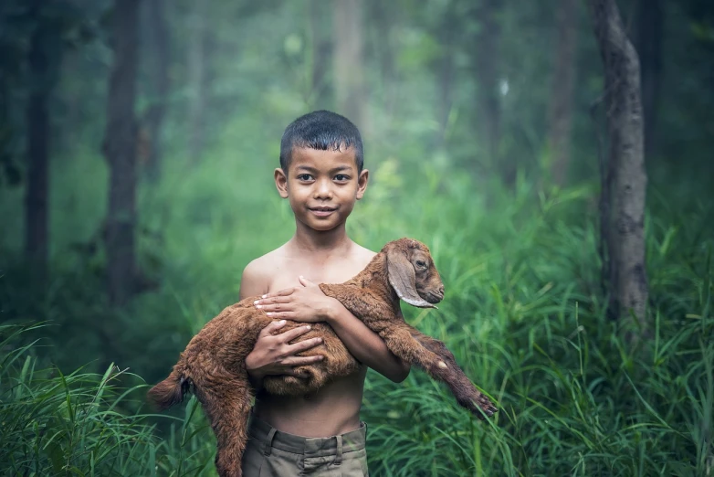 a young boy holding a baby goat in a forest, a picture, inspired by Steve McCurry, sumatraism, goat body, post-processed, holding a 🛡 and an 🪓, friends