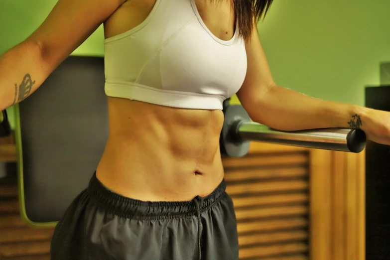 a woman standing next to a bar in a gym, pexels, arabesque, folds of belly flab, closeup photo, high details photo