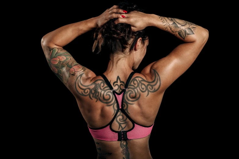 a woman with a tattoo on her back, a tattoo, by Ludovit Fulla, shutterstock, bodybuilding woman, pink and black, half body photo, high details photo