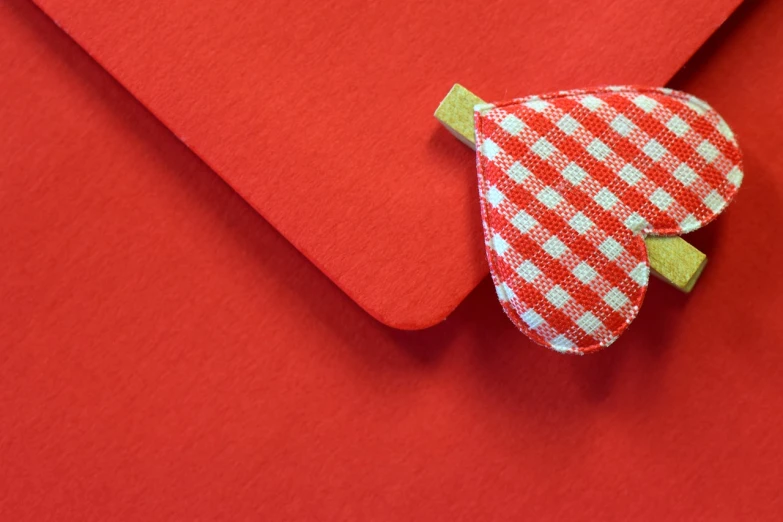 a piece of fabric sitting on top of a red envelope, by Romain brook, pexels, heart, peppermint motif, no text!, checkered pattern