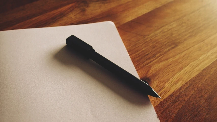 a pen sitting on top of a piece of paper, by Karl Buesgen, unsplash, wikimedia, realistic footage, miscellaneous objects, cg original