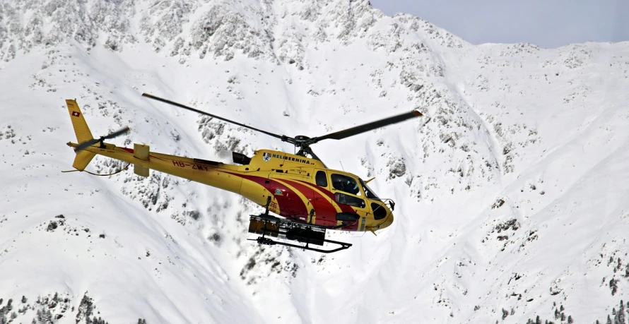 a yellow and red helicopter flying over a snow covered mountain, flickr, hurufiyya, flying emergency vehicles, chamonix, wikimedia commons, full-body-shot