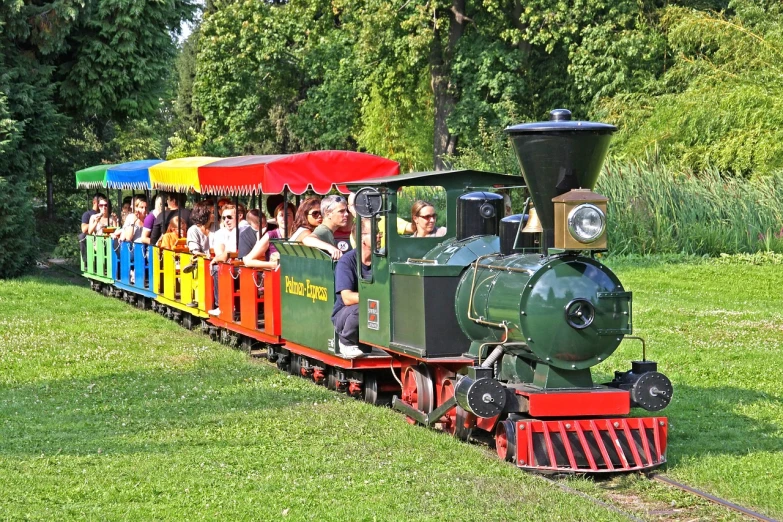 a group of people riding on top of a train, by Jan Stanisławski, shutterstock, in the park, big engine, 1998 photo, a green
