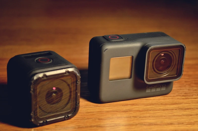 a couple of cameras sitting on top of a wooden table, by Matt Cavotta, gopro footage, front side, hero shot, 4 k detail