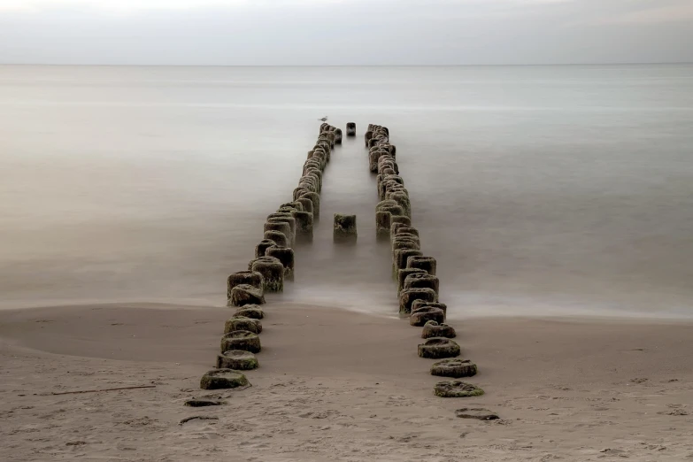 a row of wooden posts sticking out of the water, a photo, inspired by Jan Kupecký, stone colossus remains, long distance photo