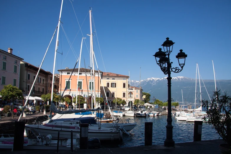 a harbor filled with lots of boats under a blue sky, a picture, by Alfredo Volpi, lamp posts, with mountains in the background, bizzaro, calatrava