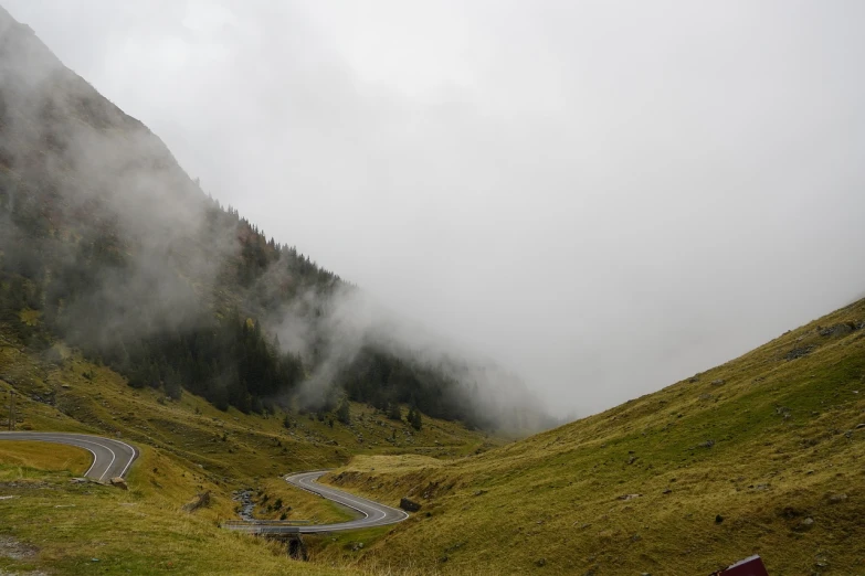 a winding road in the mountains on a cloudy day, a picture, pexels, figuration libre, very realistic. fog, swiss, romanian, nice slight overcast weather