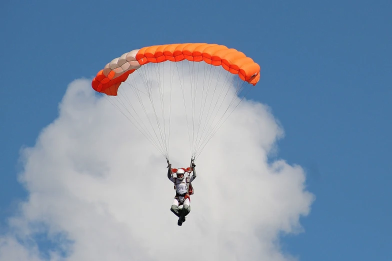 a person that is in the air with a parachute, a picture, by Tom Carapic, orange and white color scheme, wikimedia commons, helmet is off, cloud jumper