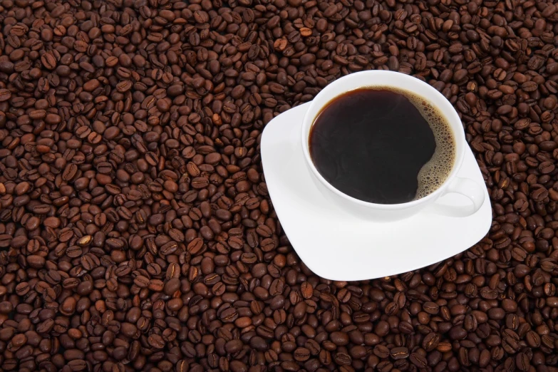 a cup of coffee sitting on top of a pile of coffee beans, photograph credit: ap, wallpaper - 1 0 2 4, full product shot, 64x64