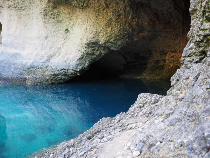 a body of water with a cave in the background, shutterstock, bahamas, details and vivid colors, looking around a corner, apulia
