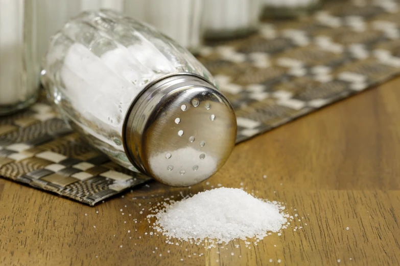 a salt shaker sitting on top of a wooden table, by Harvey Pratt, pixabay, photorealism, sugar sprinkled, sunken, organic, say ahh