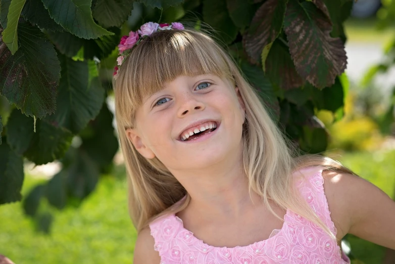 a little girl that is standing under a tree, a picture, by Maksimilijan Vanka, pixabay, portrait of a smiling, a blond, high detail portrait photo, istockphoto