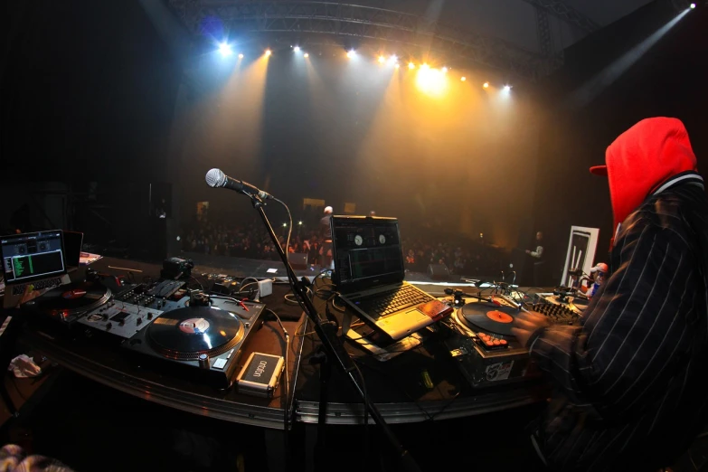 a man that is standing in front of a dj, by Matt Stewart, flickr, on an empty stage from above, extreme panoramic, audio equipments, shigeto hirai yuya