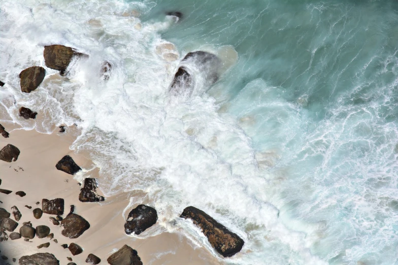 a bird's eye view of a beach with rocks and water, by John Broadley, crashing waves and sea foam, istock, clean detail, stock photo