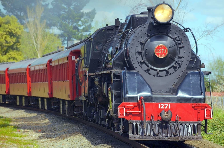 a red and black train traveling down train tracks, a portrait, inspired by Ernest Buckmaster, pixabay, large blue engines, sunny day, preserved historical, 1 2 9 7