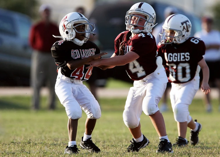 a group of young boys playing a game of football, by Scott M. Fischer, happening, maroon and white, aggressive stance, neil blevins and jordan grimmer, closeup photo