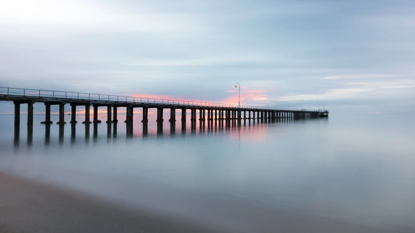 a long pier stretches out into the ocean, a tilt shift photo, inspired by Edwin Georgi, shutterstock, caulfield, long exposure outside the city, early dawn, silk