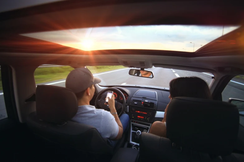 a couple of people that are sitting in a car, a picture, by Whitney Sherman, pexels, sun overhead, smartphone photo, open road, istock