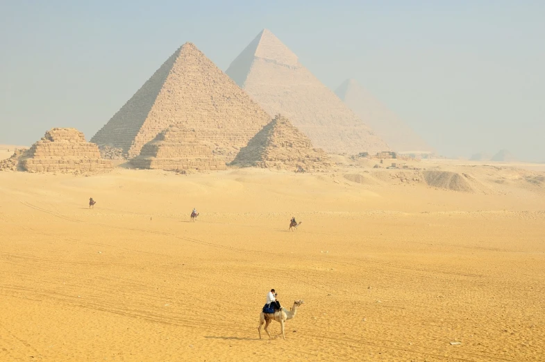 a group of people riding on the backs of camels in front of the pyramids, egyptian art, by Robert Peak, pexels, 480p, viewed from very far away, sand mists, stock photo