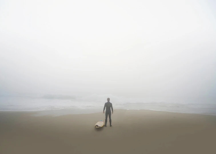 a man standing on a beach with a surfboard, by Morris Kestelman, minimalism, fog storm, michael wellen, looking in front, ; wide shot