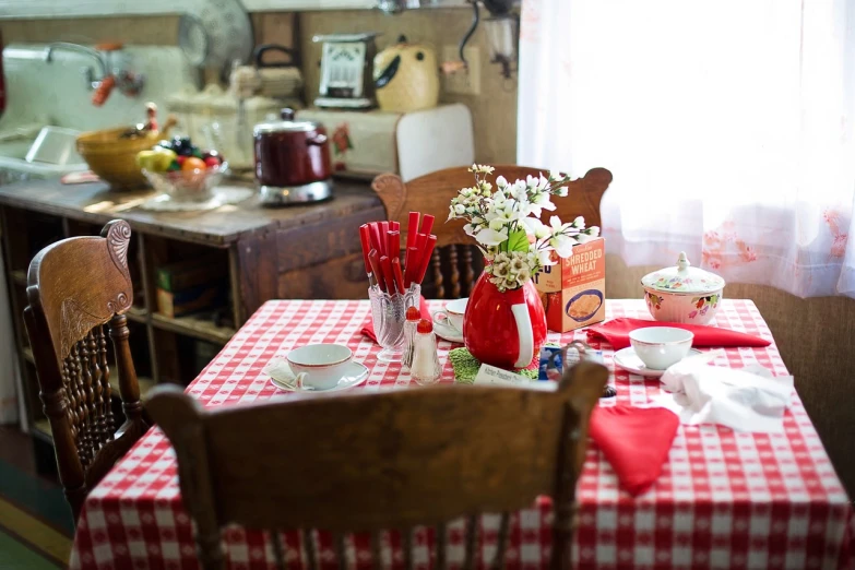 a table with a red and white checkered table cloth, by Pamela Ascherson, flickr, folk art, photo taken with sony a7r, interior of a small, illinois, movie set”