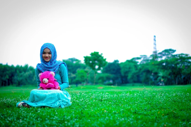 a woman sitting in the grass with a pink teddy bear, by Basuki Abdullah, flickr, hurufiyya, red and cyan theme, islamic, park background, toy photo