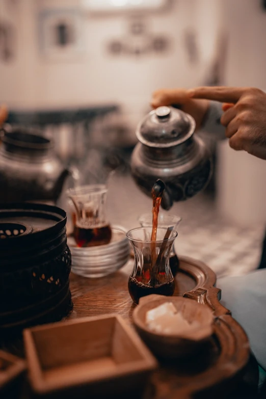 a person pouring tea into a cup on a table, a still life, by Romain brook, pexels contest winner, arabica style, traditional chinese, 💣 💥, teapots