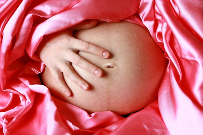 a pregnant woman with her hands on her belly, inspired by Anne Geddes, pixabay, ultrafine detail ”, pink body, satin, photograph credit: ap