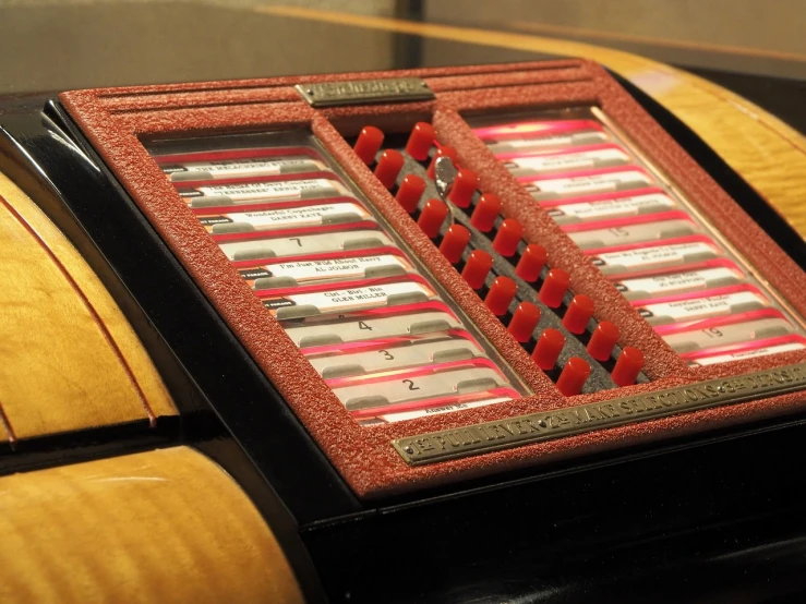 a close up of a musical instrument on a table, by Robert Brackman, assemblage, cigarrette boxes at the table, pink and red color scheme, list, close up to the screen