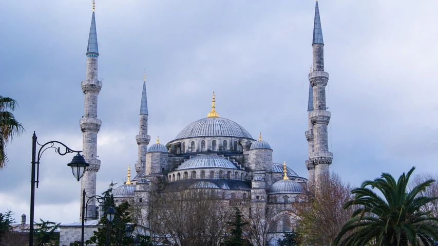 a group of people sitting on a bench in front of a building, a photo, inspired by Lü Ji, flickr, hurufiyya, minarets, blue and gray colors, hdr detail, with great domes and arches