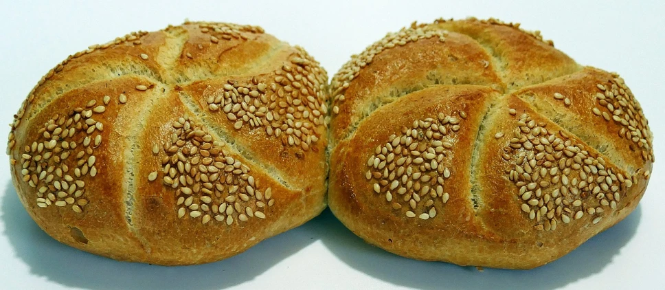 a couple of bread buns sitting on top of a table, by Karl Völker, pixabay, art nouveau, luscious with sesame seeds, rotated left right front back, detailed zoom photo, assyrian