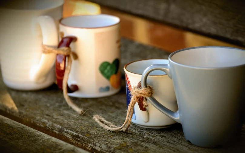 a couple of cups sitting on top of a wooden bench, a picture, pexels, folk art, cords, in a row, white mug, extremely higly detailed