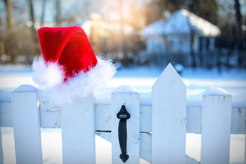 a santa hat sitting on top of a white fence, a photo, by Stefan Gierowski, shutterstock, in front of the house, stock photo, gate, hi-res photo