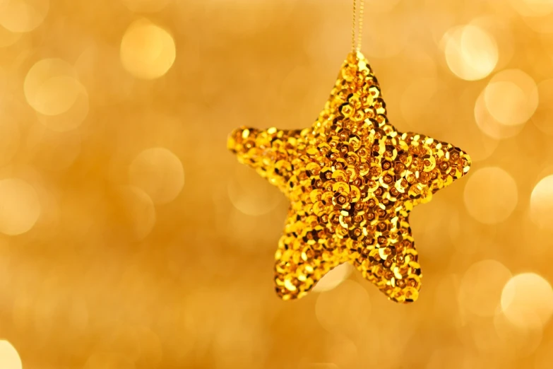 a gold star ornament hanging from a string, pexels, digital art, unrefined sparkling gold nugget, yellow wallpaper, zoomed in, sequins