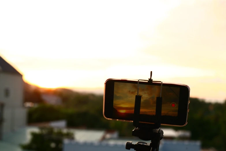 a cell phone sitting on top of a tripod, a picture, by Robbie Trevino, shutterstock, sun set, mobile still frame. 4k uhd, old distorted camcorder video, home video footage